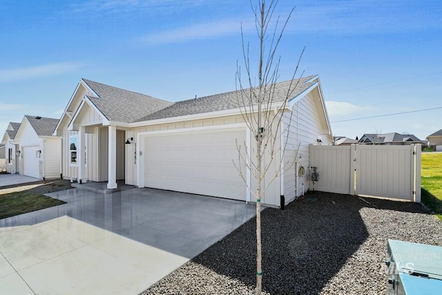 view of front facade featuring a gate, driveway, a garage, and a shingled roof