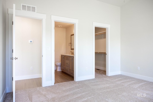 unfurnished bedroom featuring a closet, visible vents, a sink, carpet floors, and a spacious closet