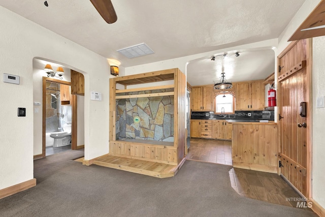 1219 N Indiana, Caldwell, ID 83605 - kitchen with visible vents, a sink, dark countertops, dark colored carpet, and arched walkways