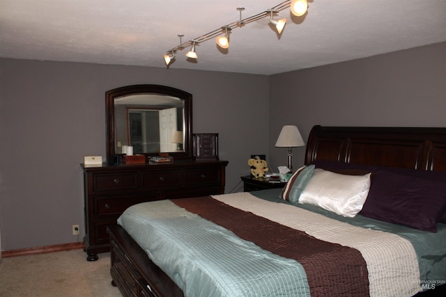 carpeted bedroom featuring rail lighting