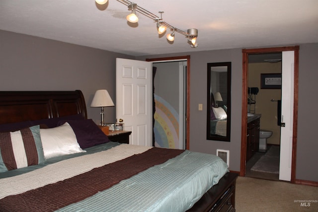 carpeted bedroom featuring track lighting and connected bathroom