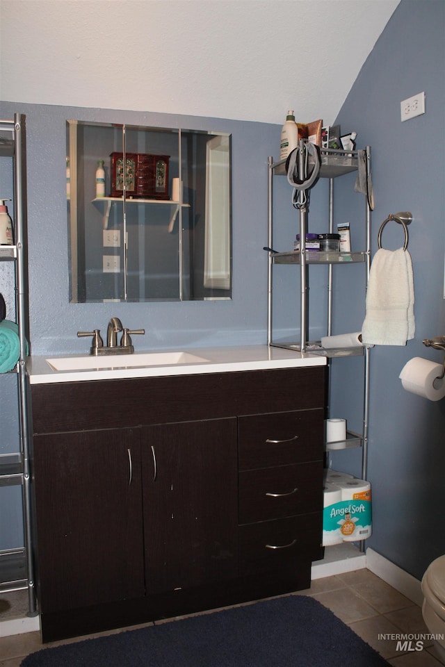 bathroom featuring vaulted ceiling, vanity, toilet, and tile floors