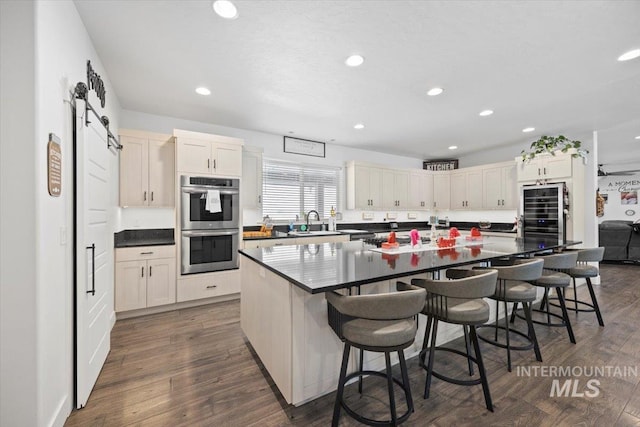 kitchen featuring stainless steel double oven, a kitchen breakfast bar, dark hardwood / wood-style flooring, and a kitchen island