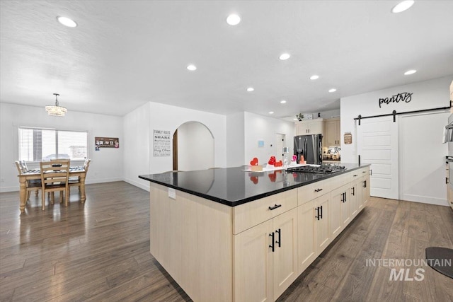 kitchen with decorative light fixtures, a center island, appliances with stainless steel finishes, dark hardwood / wood-style flooring, and a barn door