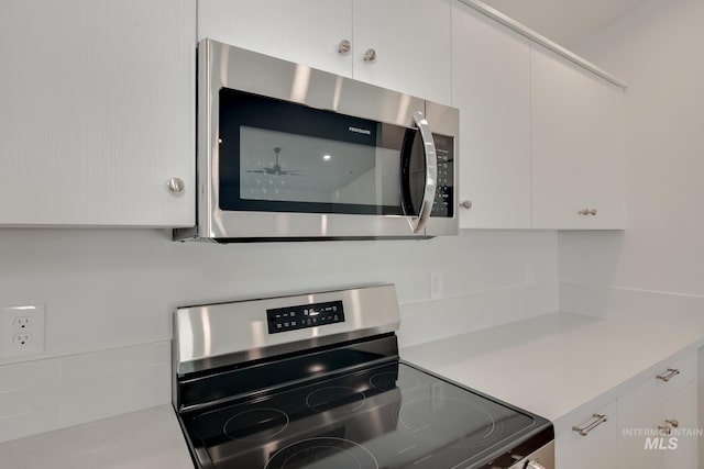 kitchen with white cabinetry, stainless steel appliances, and ceiling fan