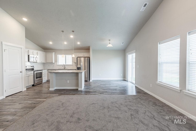 kitchen with a kitchen island, open floor plan, appliances with stainless steel finishes, white cabinets, and a sink