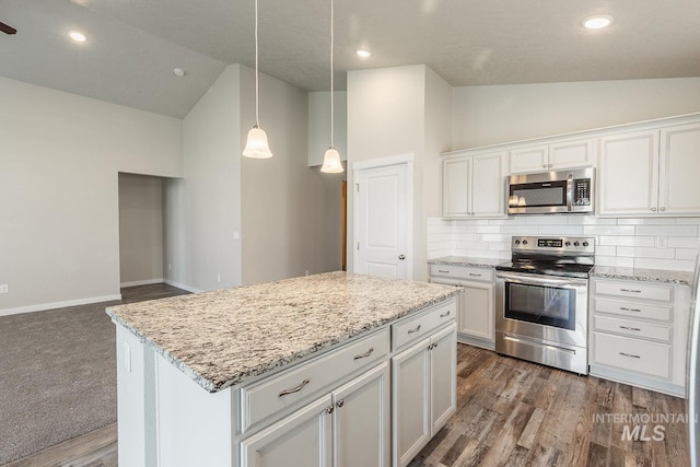 kitchen with light stone countertops, white cabinets, appliances with stainless steel finishes, backsplash, and a center island