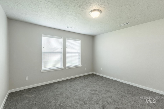 unfurnished room featuring visible vents, dark carpet, and baseboards