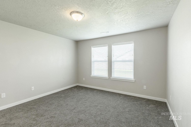 empty room with dark colored carpet, visible vents, baseboards, and a textured ceiling