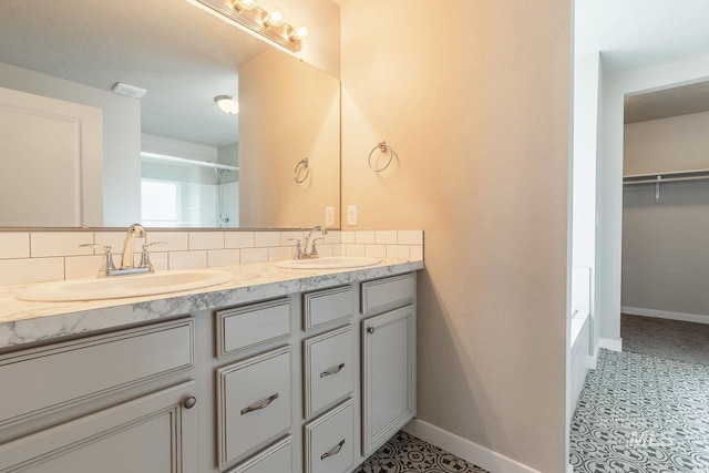 full bathroom featuring double vanity, baseboards, and a sink
