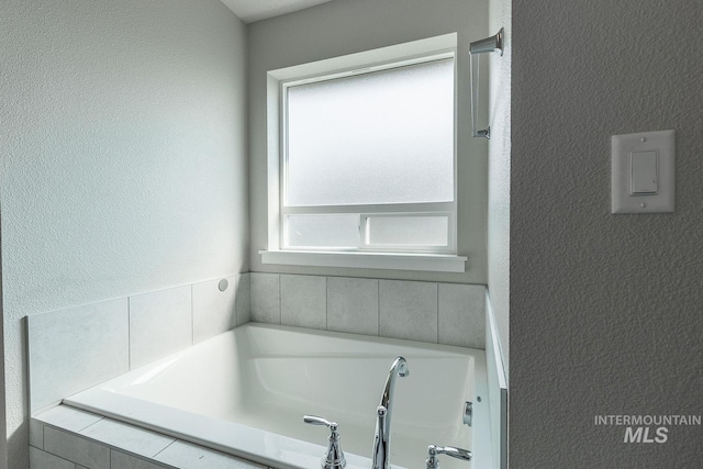 full bathroom featuring a bath and a textured wall