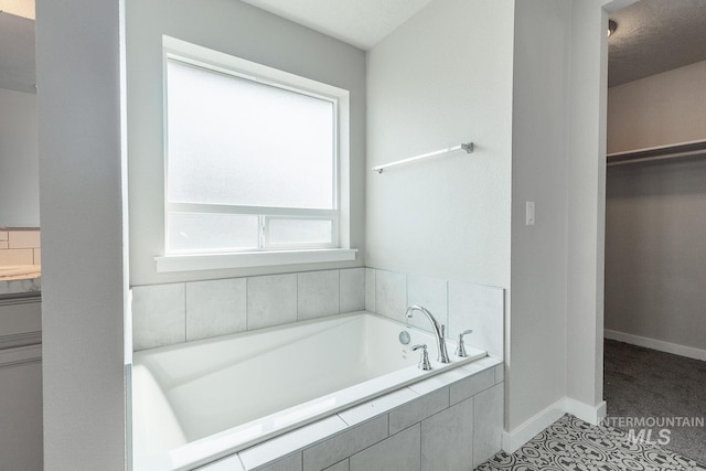bathroom with tile patterned floors, a walk in closet, baseboards, and a bath