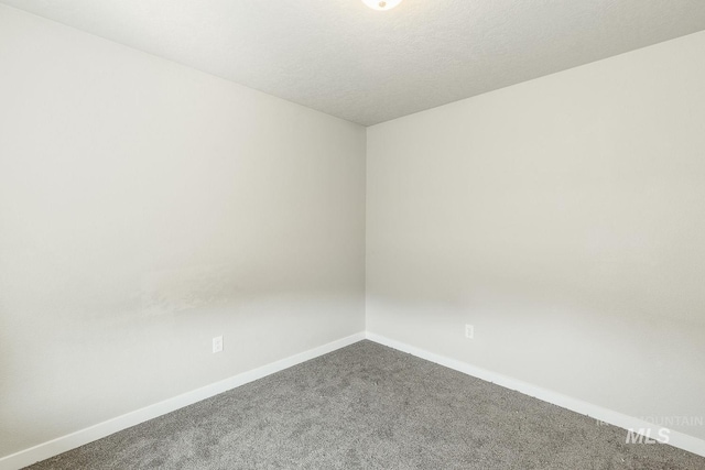 carpeted spare room featuring baseboards and a textured ceiling