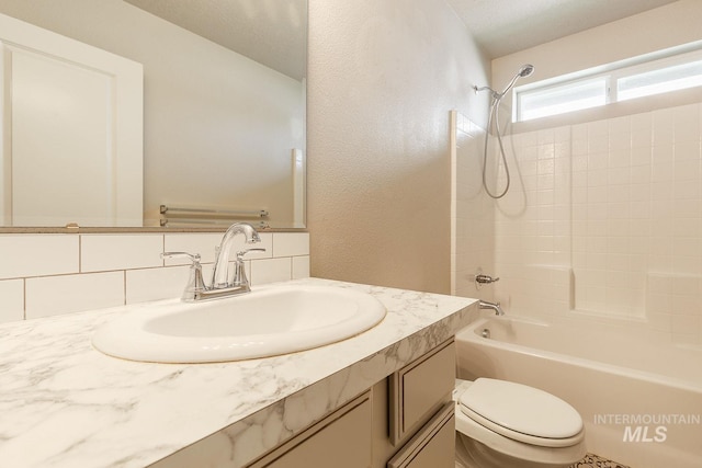 bathroom with vanity, bathtub / shower combination, toilet, a textured wall, and backsplash