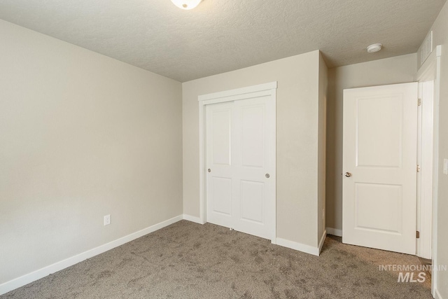 unfurnished bedroom with a closet, baseboards, carpet, and a textured ceiling