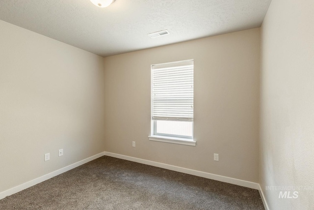 unfurnished room featuring baseboards, visible vents, dark carpet, and a textured ceiling