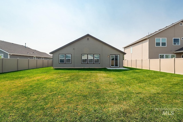back of house with a yard and a fenced backyard