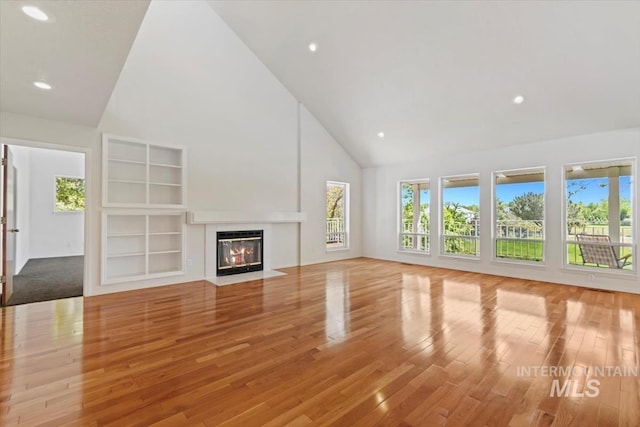 975 W Meander Ct, Eagle, ID 83616 - unfurnished living room featuring high vaulted ceiling, wood finished floors, plenty of natural light, a fireplace with flush hearth, and recessed lighting