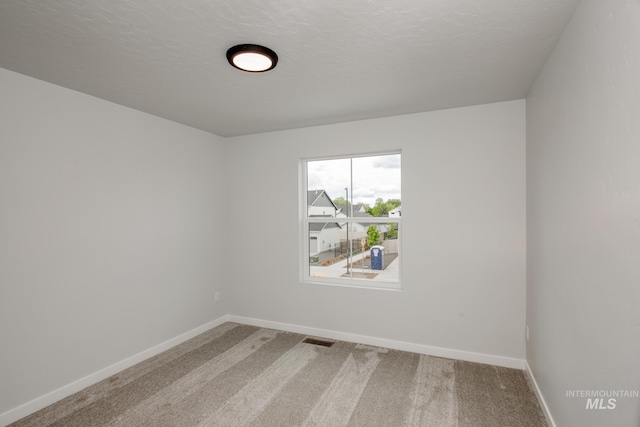 carpeted spare room featuring a textured ceiling