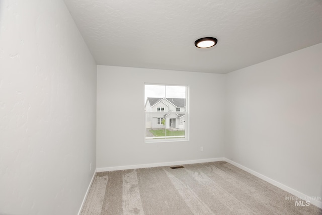 empty room with carpet and a textured ceiling