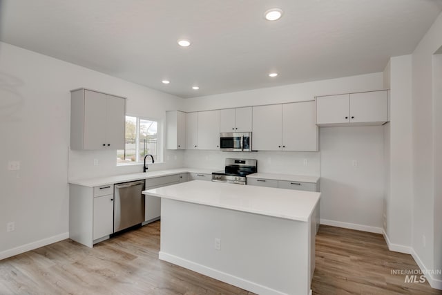 kitchen with white cabinets, appliances with stainless steel finishes, light wood-type flooring, and a kitchen island