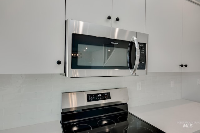 kitchen with backsplash, white cabinetry, and stainless steel appliances