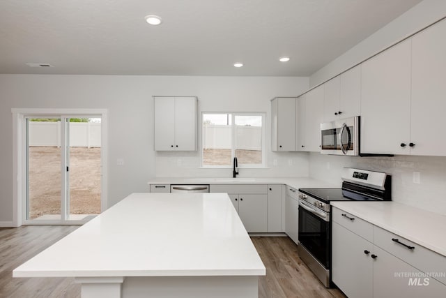 kitchen with white cabinets, a kitchen island, appliances with stainless steel finishes, and sink