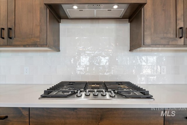 kitchen featuring dark brown cabinetry, ventilation hood, tasteful backsplash, and stainless steel gas stovetop