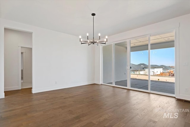 unfurnished room featuring a notable chandelier and dark hardwood / wood-style floors