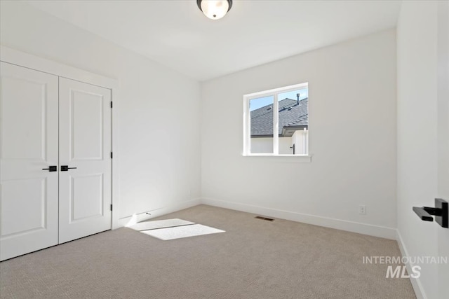 unfurnished bedroom featuring a closet and light colored carpet