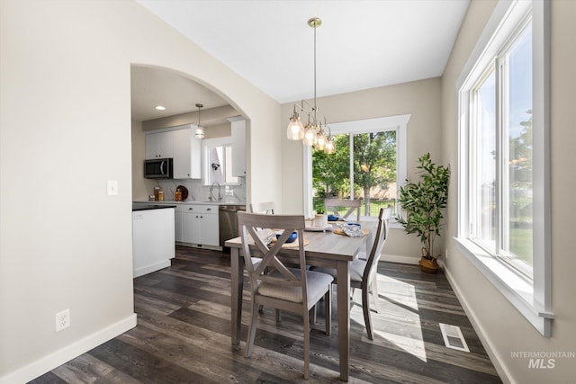 12384 S Abbott Downing Way, Nampa, ID 83686 - dining room with baseboards, arched walkways, dark wood-style floors, and a chandelier