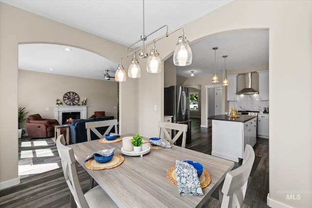 12384 S Abbott Downing Way, Nampa, ID 83686 - dining area featuring arched walkways, a warm lit fireplace, and dark wood-type flooring