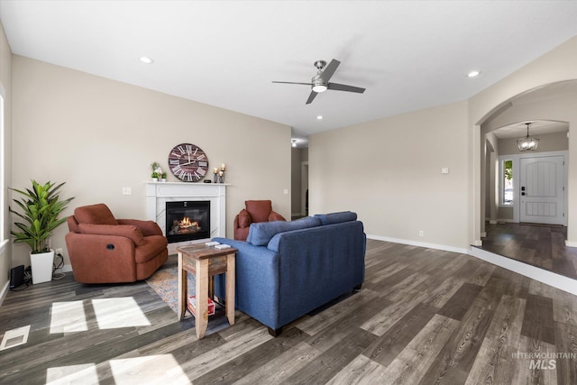 12384 S Abbott Downing Way, Nampa, ID 83686 - living room with arched walkways, dark wood-style flooring, a glass covered fireplace, ceiling fan, and recessed lighting