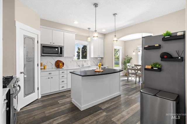 12384 S Abbott Downing Way, Nampa, ID 83686 - kitchen with stainless steel appliances, a sink, dark wood finished floors, white cabinetry, and tasteful backsplash