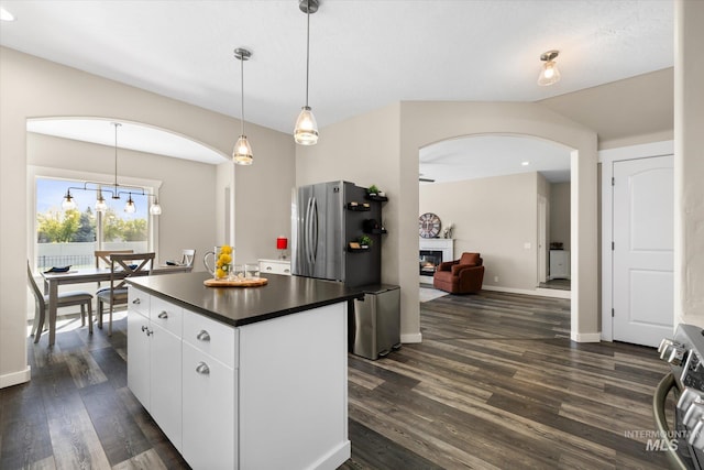 12384 S Abbott Downing Way, Nampa, ID 83686 - kitchen featuring dark countertops, arched walkways, a center island, white cabinets, and dark wood-style floors