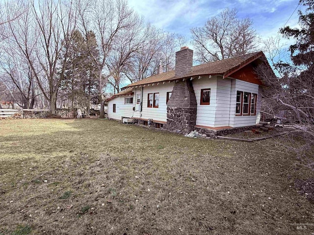 view of side of property featuring a chimney and a lawn