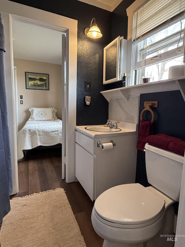 half bathroom with vanity, wood finished floors, and toilet