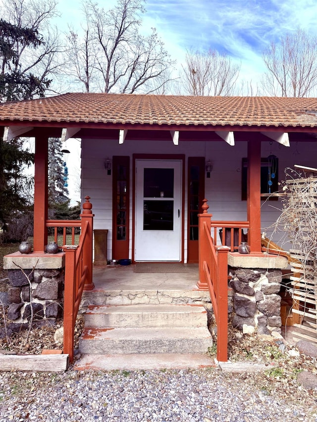 property entrance with a porch and a tile roof