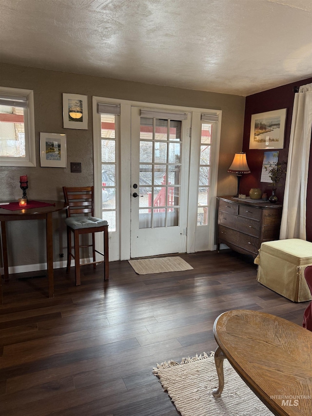 doorway featuring a textured ceiling, baseboards, and dark wood-type flooring