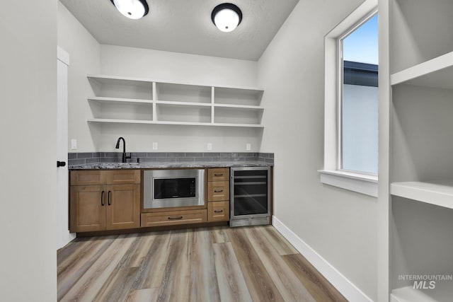 bar with light hardwood / wood-style flooring, sink, built in microwave, a textured ceiling, and wine cooler