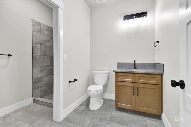 bathroom with toilet, vanity, and tiled shower