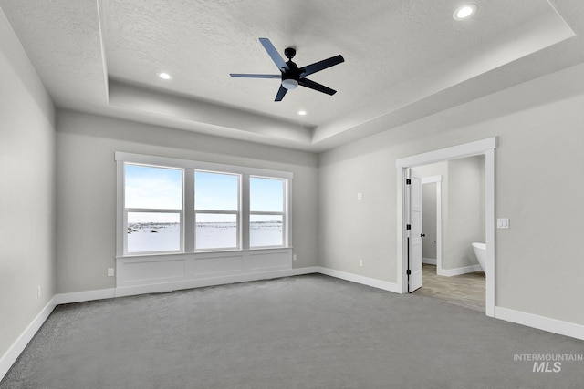 interior space featuring a textured ceiling, ceiling fan, and a raised ceiling