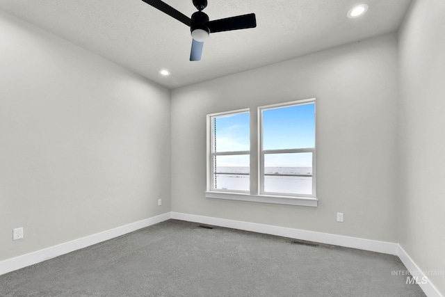 carpeted spare room featuring a textured ceiling and ceiling fan