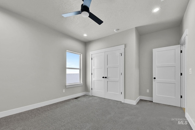 unfurnished bedroom featuring ceiling fan, carpet floors, a textured ceiling, and a closet