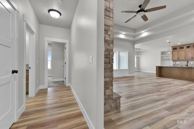 hallway with light wood-type flooring, sink, and a textured ceiling