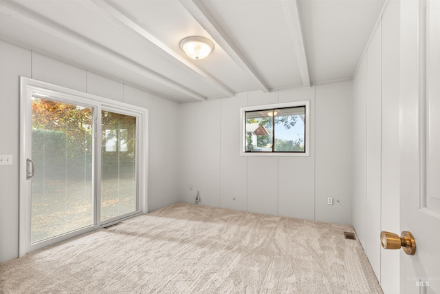 carpeted spare room featuring beamed ceiling