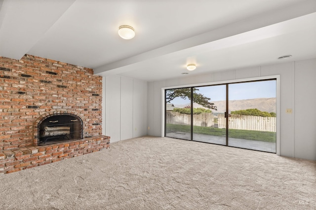 unfurnished living room with a fireplace, a mountain view, and carpet flooring