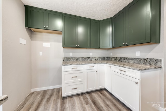 kitchen with light hardwood / wood-style floors, white cabinetry, and light stone countertops