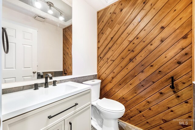 bathroom with vanity, a skylight, toilet, and wood walls