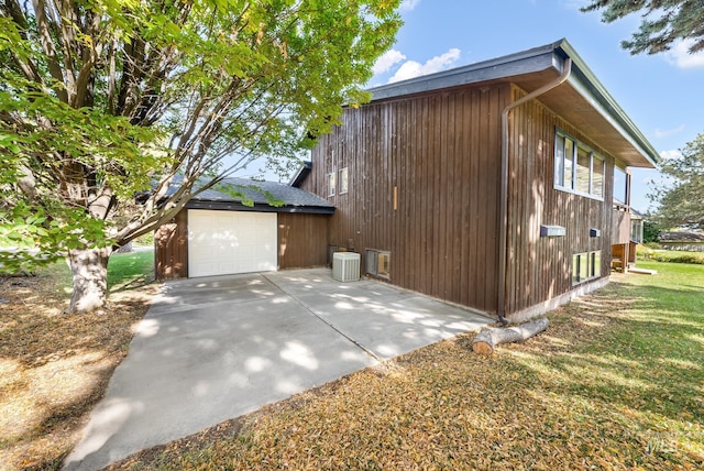 view of side of property with central AC, an outdoor structure, a garage, and a lawn